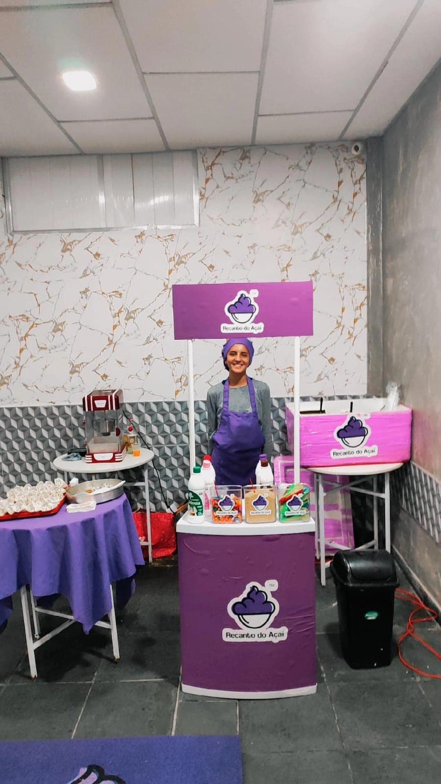 Estação de açaí montada com atendente uniformizada no salão de festas